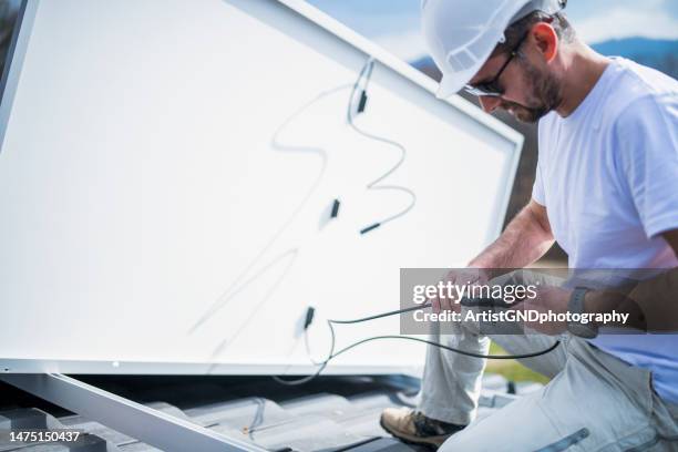 solar panel installer installing solar panels on roof of modern house. - cable installer stock pictures, royalty-free photos & images