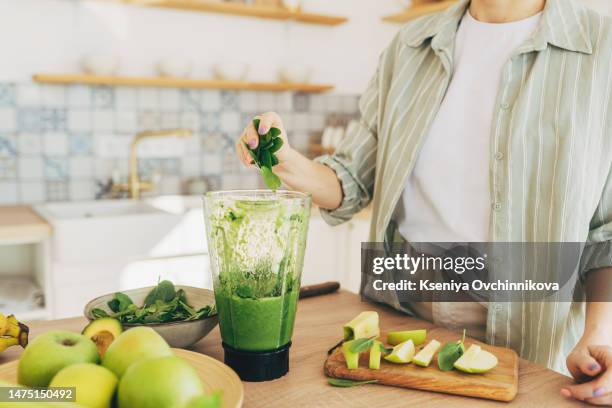 young man preparing healthy green smoothie in kitchen - detox stockfoto's en -beelden