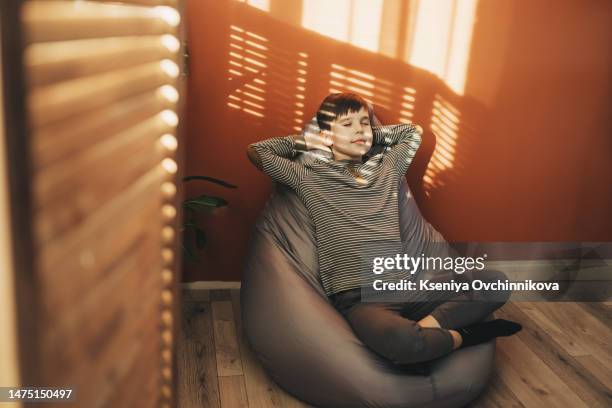 relaxed boy laying on a comfortable green beanbag isolated on white background - beanbag chair stockfoto's en -beelden