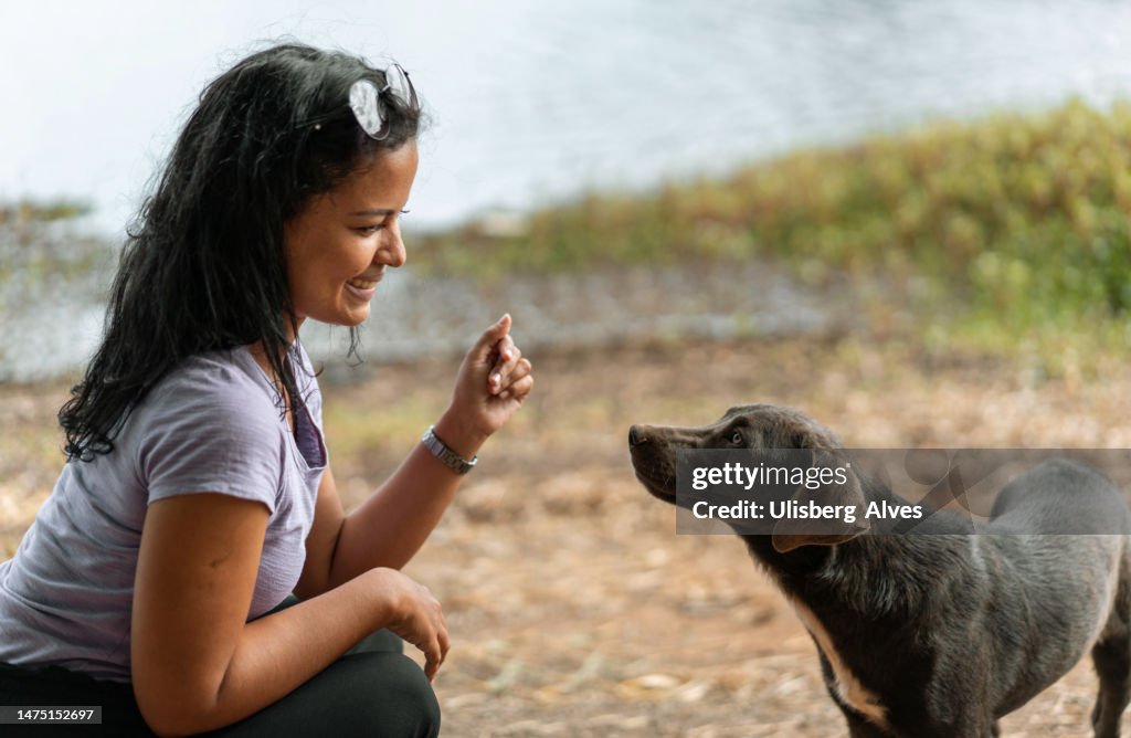 Woman playing with her dog in front of the lake