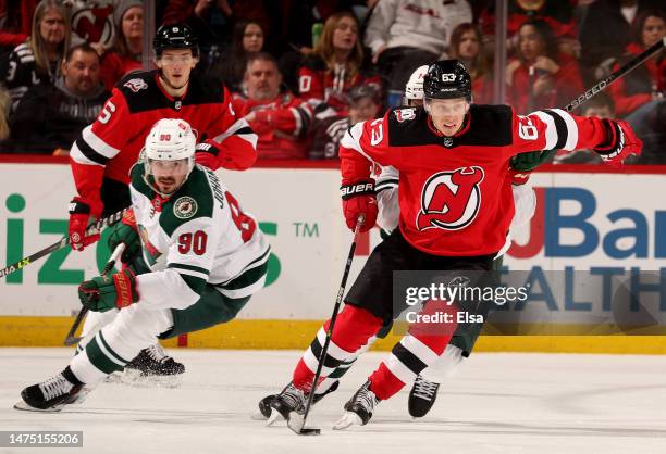 Jesper Bratt of the New Jersey Devils takes the puck as Joel Eriksson Ek and Marcus Johansson of the Minnesota Wild defend during the second period...