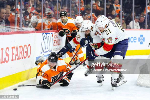 Radko Gudas and Nick Cousins of the Florida Panthers, and Wade Allison of the Philadelphia Flyers challenge for the puck during the second period at...