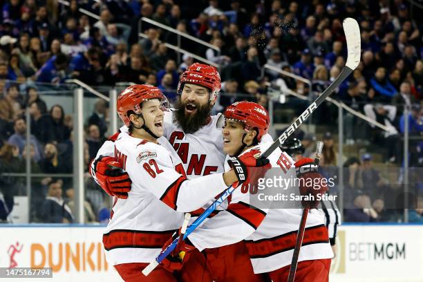 Jesperi Kotkaniemi and Brent Burns react with Teuvo Teravainen of the Carolina Hurricanes after Teravainen scored the game-winning goal during the...