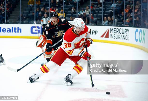 Elias Lindholm of the Calgary Flames skates the puck against Ryan Strome of the Anaheim Ducks in the first period at Honda Center on March 21, 2023...