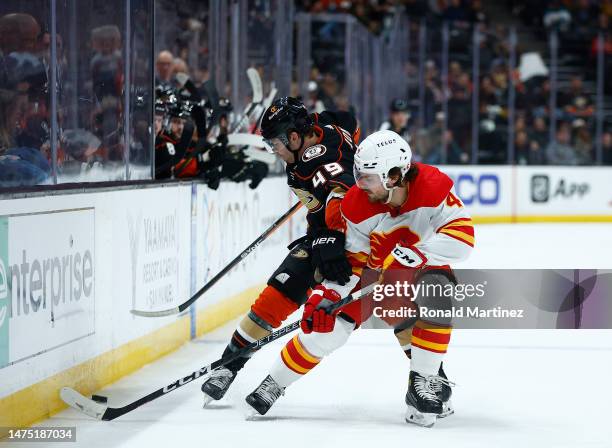 Max Jones of the Anaheim Ducks skates the puck against Rasmus Andersson of the Calgary Flames in the second period at Honda Center on March 21, 2023...