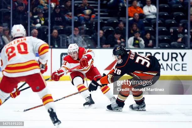 Troy Stecher of the Calgary Flames skates the puck against Derek Grant of the Anaheim Ducks in the third period at Honda Center on March 21, 2023 in...