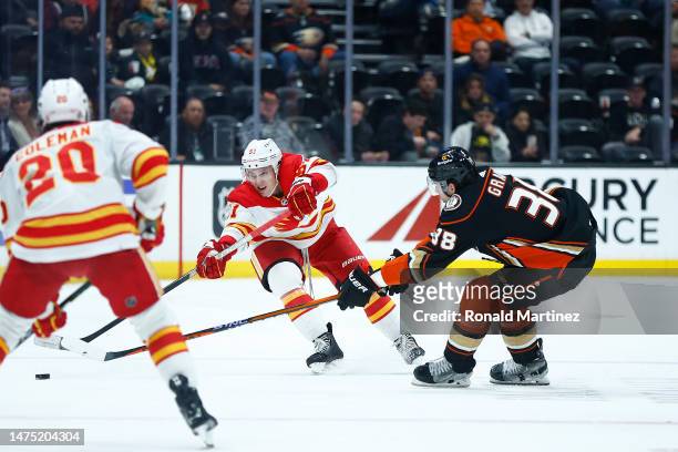 Troy Stecher of the Calgary Flames skates the puck against Derek Grant of the Anaheim Ducks in the third period at Honda Center on March 21, 2023 in...