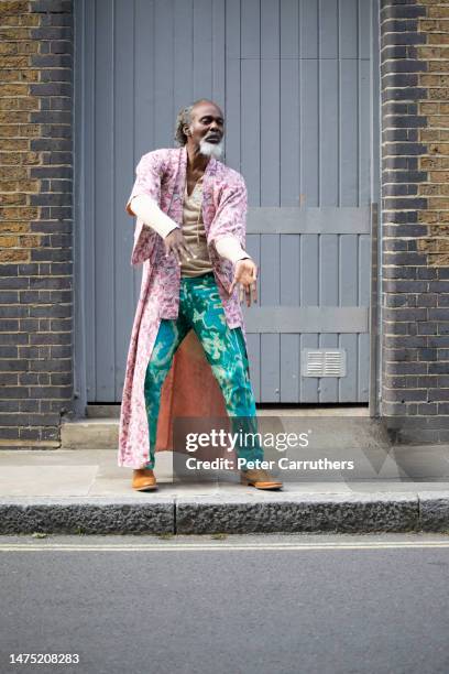 hombre maduro poco convencional bailando en la calle junto a la puerta de un almacén - london fashion fotografías e imágenes de stock