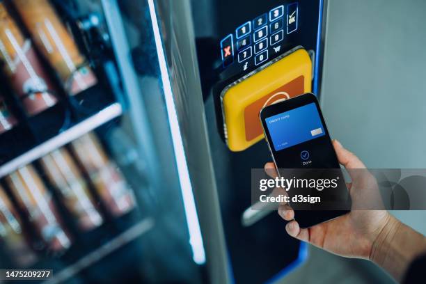 close up of woman's hand paying for the product at vending machine with contactless payment, using digital wallet on smartphone. credit card payment. e-commerce. tap to pay - mobile money stock-fotos und bilder