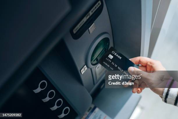 high angle shot of female hand inserting her bank card into automatic cash machine in the city. withdrawing money, paying bills, checking account balances and make a bank transfer. privacy protection, internet and mobile banking security concept - the image bank stock-fotos und bilder