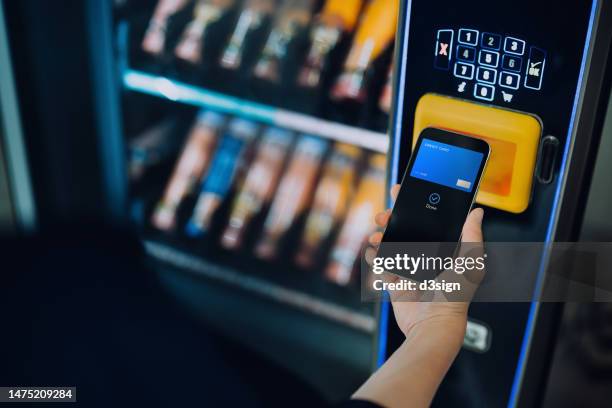 close up of woman's hand paying for the product at vending machine with contactless payment, using digital wallet on smartphone. credit card payment. e-commerce. tap to pay - verkoopautomaat stockfoto's en -beelden