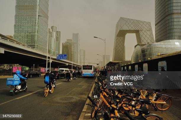 People ride on the street in a sandstorm at the Central Business District on March 22, 2023 in Beijing, China.