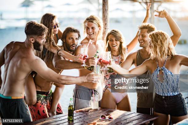 große gruppe fröhlicher freunde, die mit alkohol in einer strandbar herumtoben. - strandparty stock-fotos und bilder