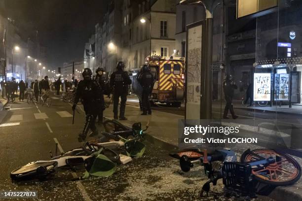 Policiers anti-émeute en intervention près d'un abribus et vélos andalisés lors d'une manifestation spontanée le 20 mars 2023 à Paris.