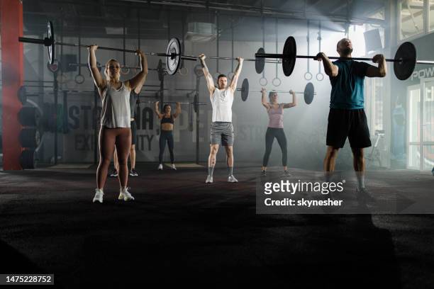 athletic people having weight training with barbells in a gym. - muscle building stockfoto's en -beelden