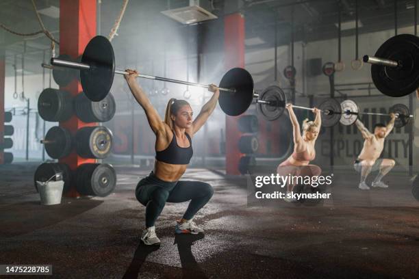 athletes exercising with barbells during cross training in a gym. - weight training stock pictures, royalty-free photos & images