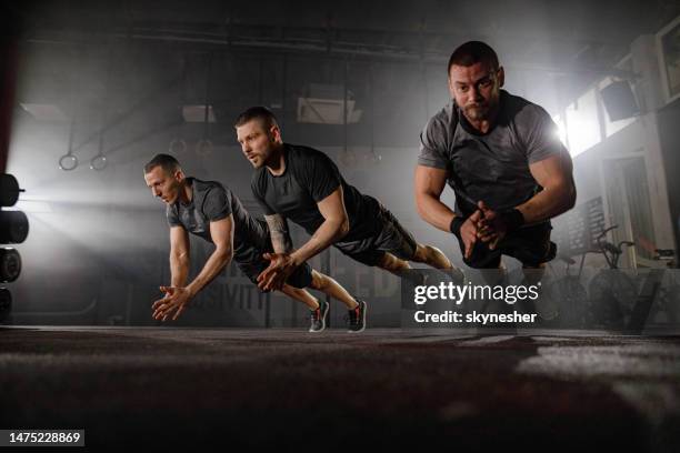 muscular build male athletes doing clap push-ups in a gym. - man muscular build stock pictures, royalty-free photos & images