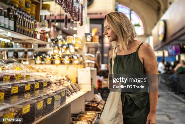 reife frau, die essen in einer markthalle betrachtet - markthalle stock-fotos und bilder