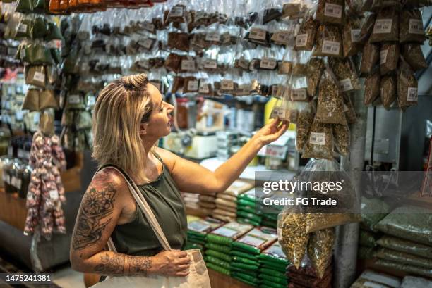 mature woman looking at herbs in a spice store - bazar de especiarias imagens e fotografias de stock