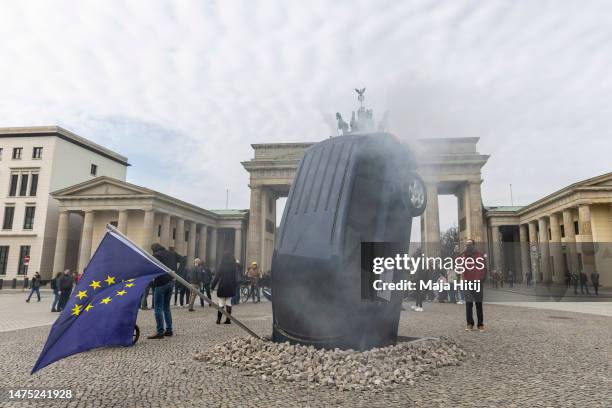 An installation by Greenpeace activists shows an SUV that is seemingly rammed into the pavement in front of the Brandenburg Gate on March 22, 2023 in...