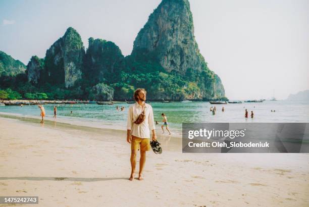 hombre caminando por la playa de railey y mirando un paisaje impresionante - krabi fotografías e imágenes de stock