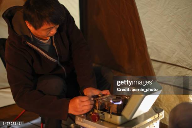 man arranges dinner in tent - gasifier stock pictures, royalty-free photos & images