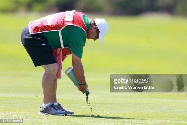 Caddie Ricci Roberts uses divot mix to repair a divot ahead of the Jonsson Workwear Open at The Club at Steyn City on March 22, 2023 in South Africa.