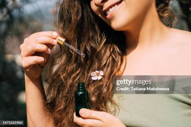 smiling woman with pipette in hand. hair moisturizer and hair care concept. - hair products ストックフォトと画像