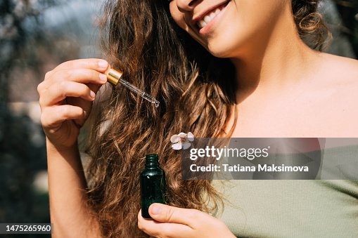 Smiling woman with pipette in hand. Hair moisturizer and hair care concept.