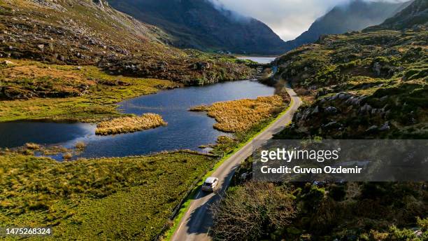 gap of dunloe, county kerry, car driving on lakeside mountain road, aerial view of scenic mountain pass, aerial nature and road view, aerial view of winding road, nature relaxation video, car driving on winding road between mountains - ireland aerial stock pictures, royalty-free photos & images