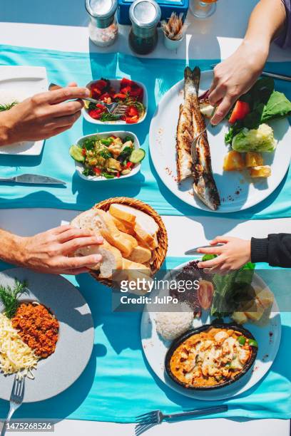 top view of dinner table with fish, salad, bread, spaghetti and chicken - blue plate stock pictures, royalty-free photos & images