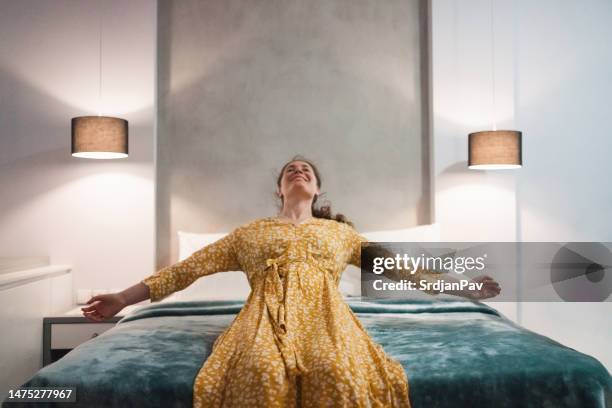 woman jumping on a hotel bed - person falling mid air stock pictures, royalty-free photos & images