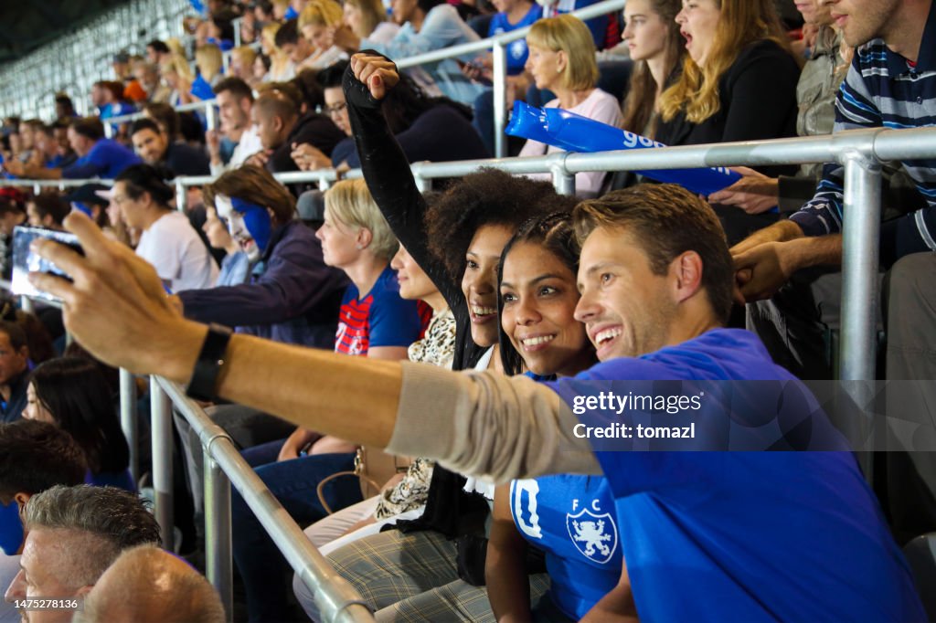 Young people at footbal match making a selfie