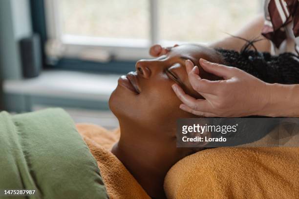 facial massage by professional woman for beautiful black woman - masseuse stock pictures, royalty-free photos & images