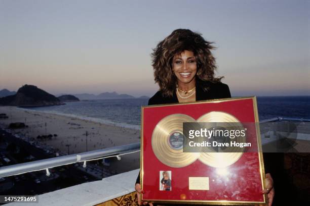 Tina Turner shows her gold discs on a balcony overlooking Copacabana Beach in Rio de Janeiro, while on her tour in Brazil in 1988.