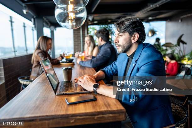 mature businessman using laptop in the restaurant on the rooftop - laptop smartphone stock pictures, royalty-free photos & images