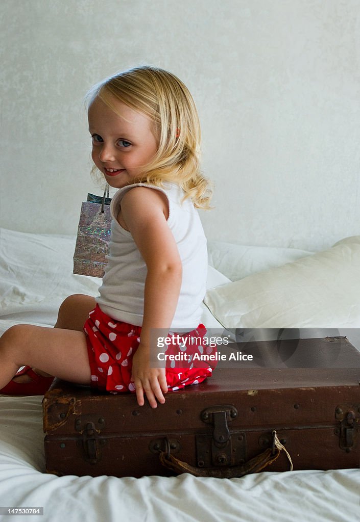 Little girl playing on vintage suitcase