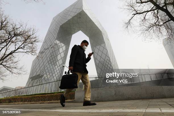 Man walks past the China Central Television headquarters building during a sandstorm on March 22, 2023 in Beijing, China.