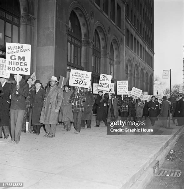 General Motors employees on the picket line - with placards reading 'Hitler Burned Books, GM Hides Books', 'What Have the DuPonts got that we haven't...