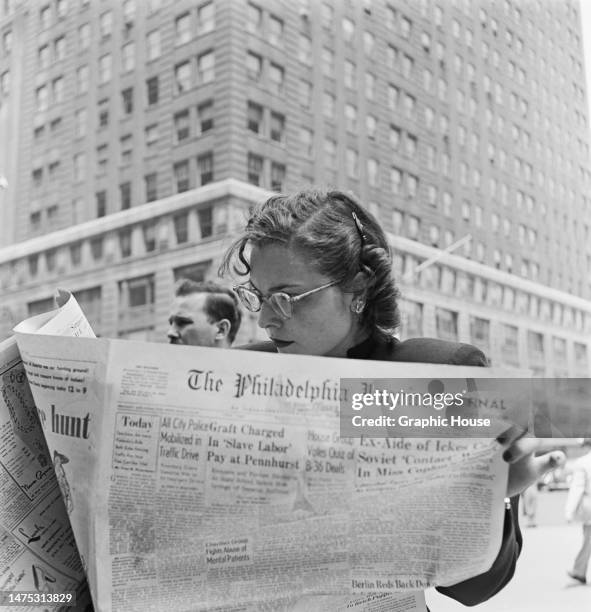Woman reads an edition of the Philadelphia Inquirer, in Philadelphia, Pennsylvania, circa 1950. Among the headlines on the front page of the...