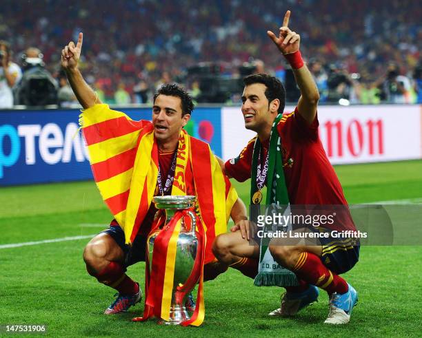 Xavi Hernandez and Sergio Busquets of Spain pose with the trophy following victory in the UEFA EURO 2012 final match between Spain and Italy at the...