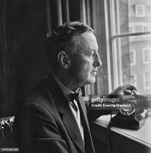 Author Ian Fleming with a hand on the receiver of a telephone in his study, April 4th, 1960. He was promoting a book of new 'James Bond' short...