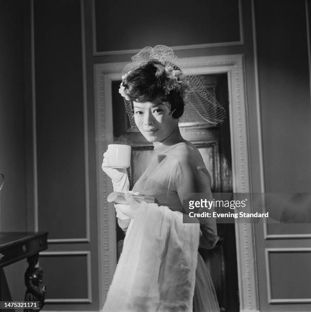Actress Yoko Tani posing with a hot drink at the time of her film 'Piccadilly Third Stop', March 31st, 1960.