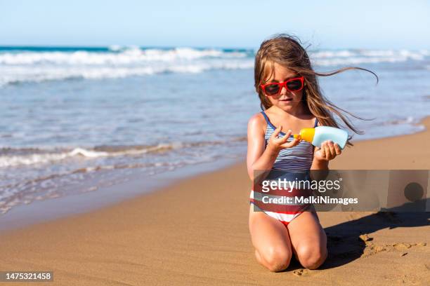 niña aplicando protector solar en la playa - girls sunbathing fotografías e imágenes de stock