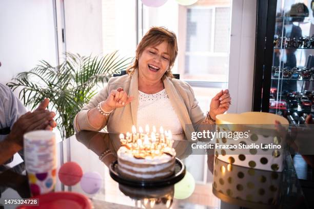 mature woman dancing while her friends sing happy birthday to her at home - anniversary cake stock pictures, royalty-free photos & images