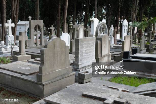 the city cemetery with old unkempt graves. stone tombstones, metal crosses. city cemetery. gravestones and stone crosses, abandoned and overgrown with grass graves of unknown people. the concept of death, the end of life, sadness, sorrow and loneliness. - cemitério imagens e fotografias de stock