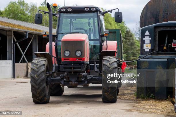 economic and environmental impact of tractors - tractor filling up with fuel stockfoto's en -beelden