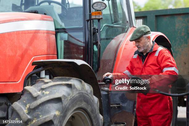 tanken der traktor des landwirts ist teuer - tractor filling up with fuel stock-fotos und bilder