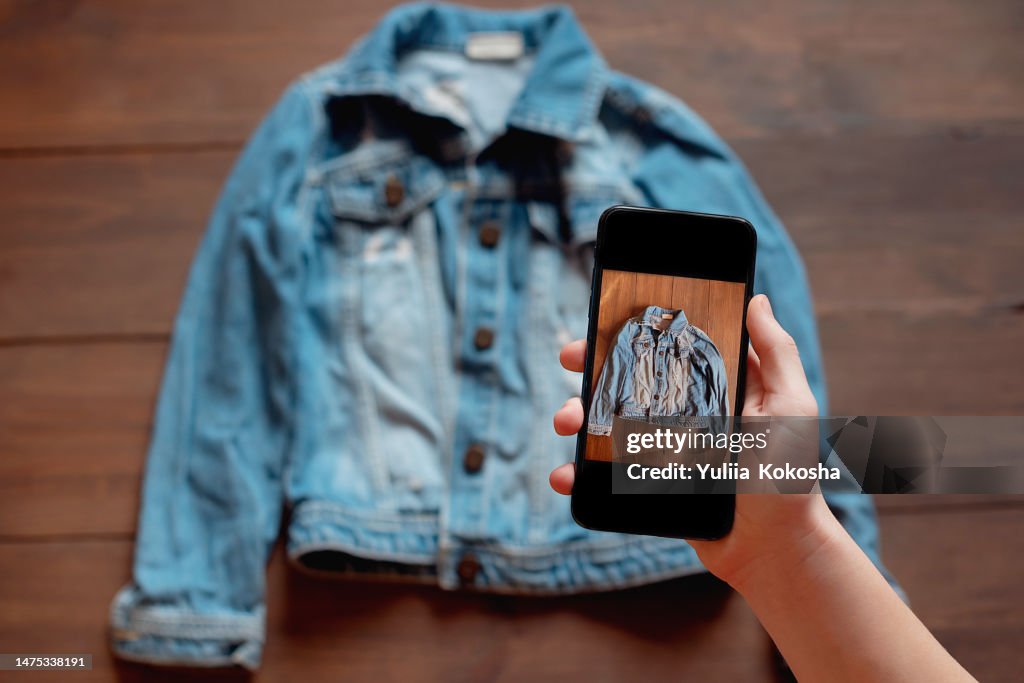 Woman taking photo of denim shirt on smartphone