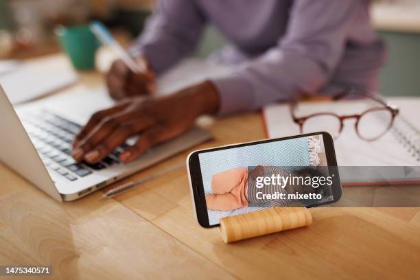 nahaufnahme der mobilen babyphone-app, während die mutter im hintergrund den laptop benutzt - babyphone stock-fotos und bilder